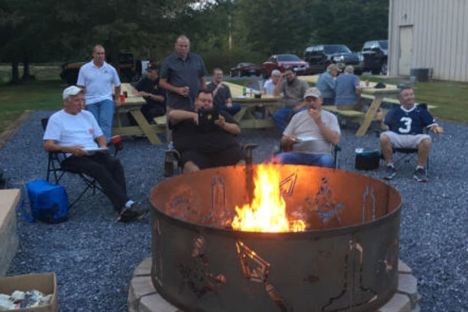 Group of men gathered around a fire pit. Group of men gathered around a fire pit.